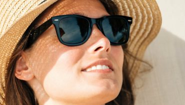 caucasian woman with sunglasses and hat under the sun