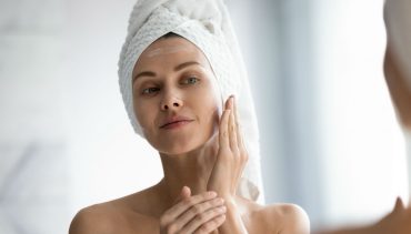 woman applying moisturizer on her face skin